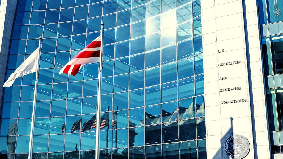 A concrete and glass building sits behind two flags on a sunny day.