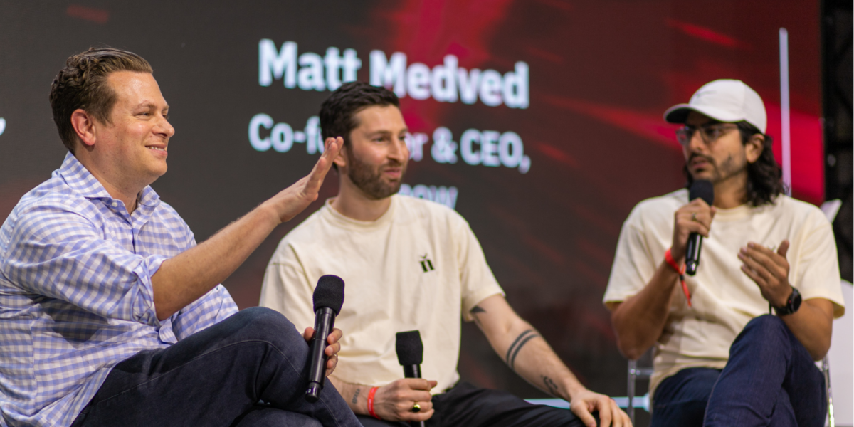 Three Men Sit On A Stage Talking.