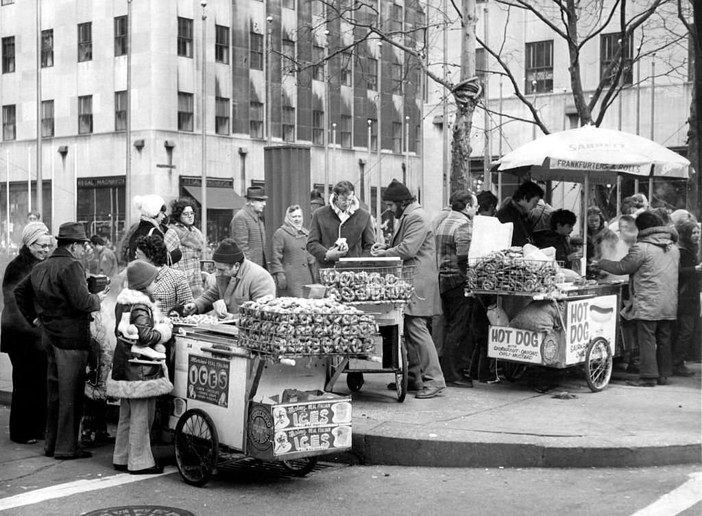 December 1975:  Street vendors selling pretzels and hot dogs in New York