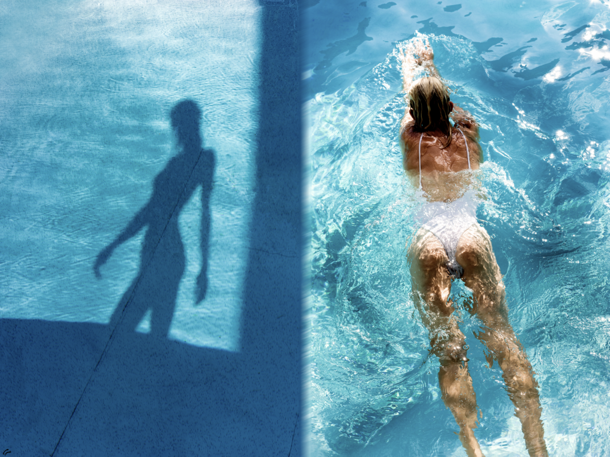 A photograph of a woman in a white one-piece swimsuit swimming in a pool from above.