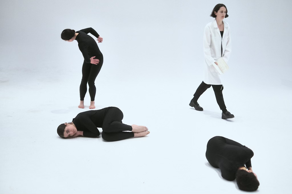 four people dance in an empty room